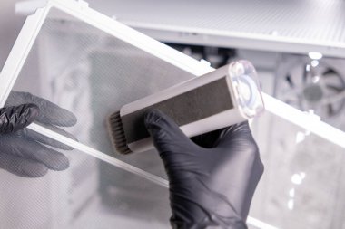 temizlik bilgisayarı filtresi, eldivenli eller, fırça kullanma, toz temizleme, bakım süreci, bilgisayar bakımı, bileşenleri temiz tutma, teknoloji hijyeni