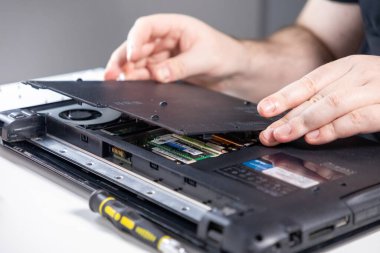 İç bakım için dizüstü bilgisayar kapağı kaldırılıyor. RAM, soğutma sistemi ve tornavida gibi bileşenleri gösteriyor.