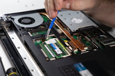 applying thermal paste to laptop CPU area during maintenance, visible RAM, cooling fan, and hard drive components clipart