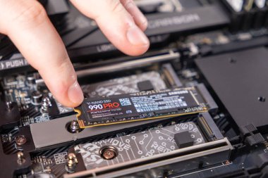 Poznan, Polonya - 25 Kasım 2024: SAMSUNG 4TB M.2 PCIe Gen4 NVMe 990 PRO SSD yükleyen teknisyen, yüksek hızlı depolama teknolojisi sergiliyor.
