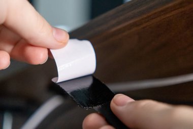 Kablo organizasyonu için ahşap masanın altına koymak için cırt cırtlı kayış desteğini soyuyordum.