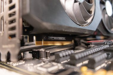 Yüksek performanslı bilgisayarlar için altın konektör iğneleri ve soğutma vantilatörleri sergilenen bir anakart üzerine kurulmuş bir grafik kartının yakın plan görüntüsü