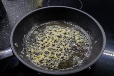 Çubuksuz tavada baloncuklu tereyağında kızartılmış sarımsak yemek pişirmek için altın ve aromatik bir zemin oluşturur.