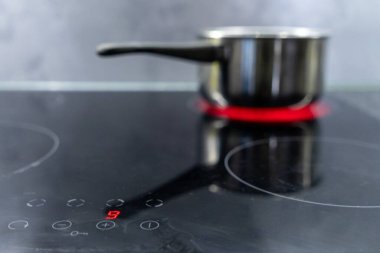 Paslanmaz çelikten bir tencerede kırmızı ısıtma ışığı ve dijital sıcaklık görüntüsü olan kaynar su.