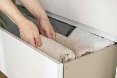 Temiz depolama ve temiz ev düzenlemesi için yumuşak bej kumaşı dikkatlice katlayarak çekmeceye havlu yerleştirmek