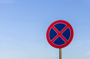 Açık mavi gökyüzü arkaplanına karşı kırmızı ve mavi renkli durdurma işareti yok, trafik yönetmeliği ve güvenliği simgeliyor
