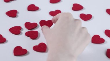 Kameraya yakın kırmızı bir kalp süslemesi, arka planda dağınık kalpler, romantik Sevgililer Günü odak noktası.