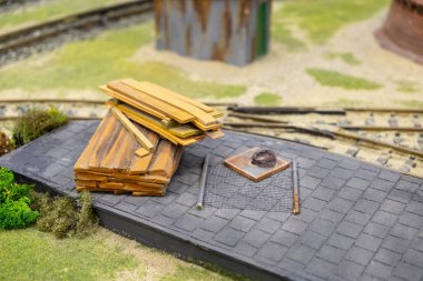 Demiryolu raylarının yakınındaki asfalt bir platforma ahşap kalaslar ve metal çubuklar yığını, açık hava depolama alanında inşa malzemeleri.