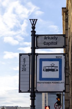 Wroclaw, Poland - January 25, 2025: tram stop sign with Arkady Capitol name route numbers and double stop symbol under clear sky in urban setting clipart