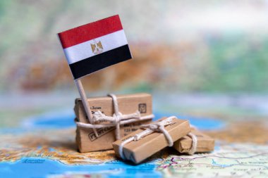 Dünya haritasındaki paketlerin yanında Mısır bayrağı var. Dünya ticareti. Mal ihracatı ve ithalatı. Ülkenin ekonomisi..