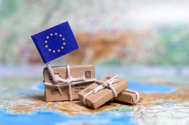 Dünya haritasındaki paketlerin yanında Avrupa Birliği bayrağı var. Dünya ticareti. Mal ihracatı ve ithalatı. Ülkenin ekonomisi.