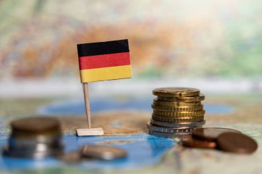 Almanya 'nın ekonomi, finans ve uluslararası ticaret ilişkilerini sembolize eden bir dünya haritasına yerleştirilmiş Alman bayrağı ve avro sikkeleri