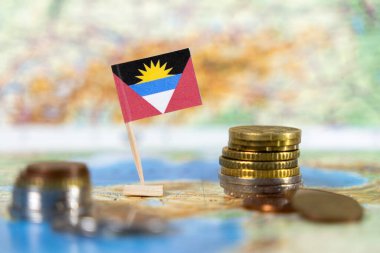 Karayip bölgesinde ekonomik büyüme, turizm ve mali kalkınmayı temsil eden bir dünya haritasında sikkeleri bulunan antigua ve barbuda bayrağı