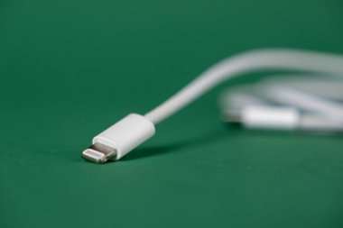 Yeşil zemin üzerinde usb konnektörlü beyaz ışık kablosu, mobil aygıtlar ve aksesuarlar için şarj kablosunun yakın plan görüntüsü