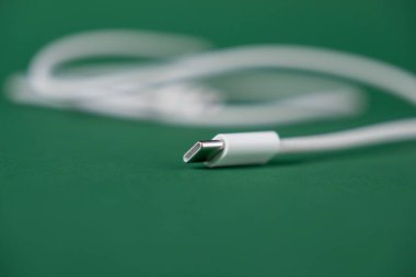 Mobil cihazlar ve elektronik aksesuarlar için modern bir şarj konnektörünün yakın plan görüntüsü olan yeşil zemin üzerinde duran beyaz usb-c kablosu