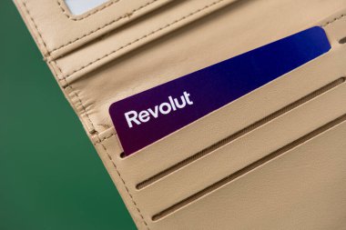 Poznan, Polonya - 26 Şubat 2025: Yeşil arka plan, modern fintech bankacılık, çevrimiçi işlemler, dijital finans, finansal güvenlik üzerine bej bir cüzdanda Revolut bankamatik kartı