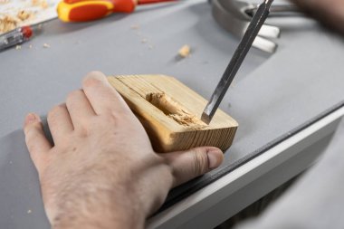 Ahşap bir blok üzerinde ahşap oyma işlemi, evdeki ahşap işçiliği projesinde hassas el oyma tekniği.