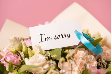 Zarif pastel çiçekli zarif bir özür buketi ve hoş bir hediye etiketinin üzerinde samimi bir 