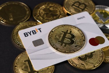 Poznan, Polonya - 7 Mart 2025: bybit bankamatik kartı ve kara arkaplan üzerindeki bitcoin paraları, kripto para işlemleri ve dijital ödemeler kavramı