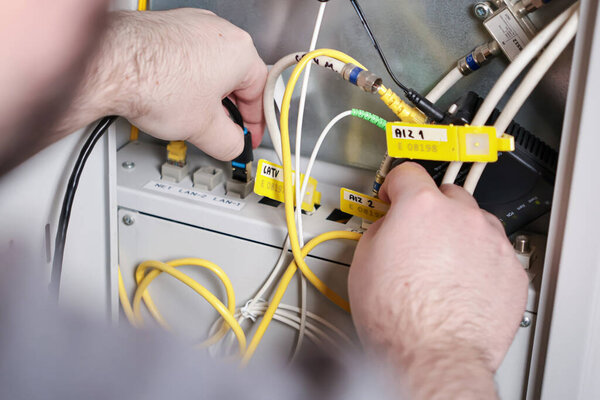 technician installing network and coaxial cables in communication panel, internet and tv setup, professional service and technology concept