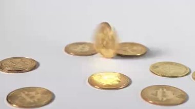 Merkezde hızla dönen bir bitcoin, beyaz bir yüzey üzerinde dağınık kripto para ile çevrili hareket bulanıklığı etkisi yaratır.