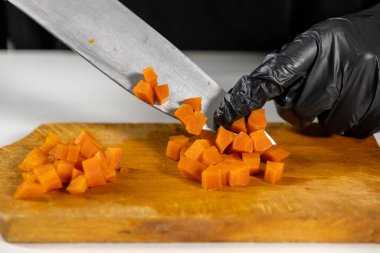 Ev yapımı salata malzemelerini hazırlarken ahşap kesme tahtasındaki küçük üniforma küplerine kaynamış havucu dikkatlice kes.