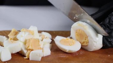 Salatalar, sandviçler ve ev yapımı yemekler için tahtanın üzerinde keskin bir bıçakla haşlanmış yumurtaları mükemmel bir şekilde doğramak.