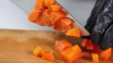 Şef ustalıkla bıçaktan taze kesilmiş havuçları çıkarırken salata, çorba ve ev yapımı dihe için malzemeler hazırlıyor.