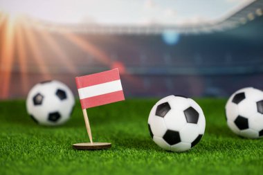 Bir stadyumda yeşil çim ve futbol topları üzerinde ulusal bayrak taşıyan Avustralya futbolu tutkusu, rekabeti, gururu ve spor kültürünü simgeliyor.