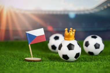 Ulusal bayrağı olan Czech Cumhuriyeti futbol sahnesi, yeşil sahada futbol topları ve stadyum arka planı, spor geleneğini ve ulusal gururu simgeliyor.