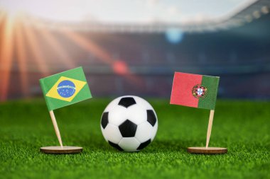 Brezilya, Portekiz futbol maçına karşı ulusal bayraklar, yeşil sahada futbol topu ve bulanık stadyum, uluslararası spor rekabetini ve mirasını simgeliyor.