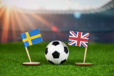 İsveç ve Birleşik Krallık futbol müsabakaları yeşil sahada bayraklar ve stadyumdaki futbol topuyla uluslararası spor müsabakalarını sembolize ediyor.