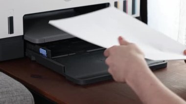 Kağıdı, ahşap masadaki modern ev yazıcısına yüklemek, ellerin ve tepsilerin kapatılması, günlük ofis görevlerini temsil etmek ve yazdırma