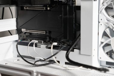 Açık PCIe yuvalarını ve bağlı güç destek kablolarını gösteren, GPU kurulumu veya güncellemesi için hazırlanmış beyaz bir bilgisayar çantasının içindeki bir bilgisayar ana kartının yakın görüntüsü