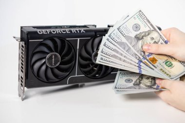 Poznan, Polonya - 28 Mart 2025: Asus GeForce RTX grafik kartı ve beyaz arka planda bulunan Amerikan dolarları pahalı bilgisayar oyunu donanımını sembolize ediyor