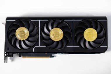 Üzerinde üç soğutucu fan bulunan yüksek performanslı bir siyah grafik kartı, kripto para madenciliğini ve GPU gücünü temsil eden her vantilatöre yerleştirilmiş altın Bitcoin jetonları ile gösteriliyor.