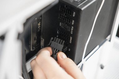 Bir teknisyen siyah bir güç kablosunu bir bilgisayar kasasının içindeki modüler güç kaynağı ünitesinin P8 portuna bağlıyor. Yakın plan bir bilgisayar oluşturmada veya güncellemede bir adım gösterir