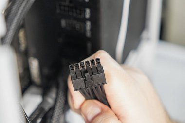 Bir teknisyen, anakart veya grafik kartı için tasarlanmış siyah bir 8-pin güç konnektörü tutuyor. Yakın çekim PC montajında veya güncellemesinde önemli bir adımı vurguluyor