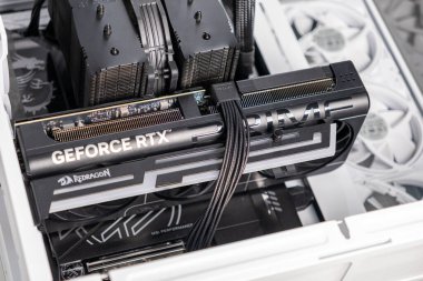 Poznan, Polonya - 30 Mart 2025: Redragon markalı GeForce RTX grafik kartının özel yapım beyaz bir masaüstüne monte edilmiş hali. Kart birbirine bağlı ve soğutucu fanlarla çevrili.