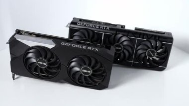 Poznan, Polonya - 27 Mart 2025: Beyaz bir yüzeye yerleştirilmiş iki ASUS GeForce RTX grafik kartının ayrıntılı görüntüsü. Resim boyut, tasarım ve serin düzen farklılıklarını vurgular