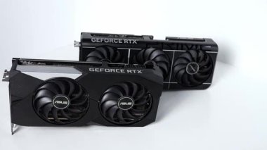 Poznan, Polonya - 27 Mart 2025: Beyaz bir yüzeye yan yana yerleştirilmiş iki ASUS GeForce RTX grafik kartı karşılaştırması. Daha serin tasarım, boyut ve yapıdaki görsel farklılıklar vurgulanmıştır