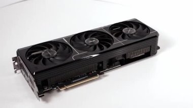 Poznan, Polonya - 27 Mart 2025: ASUS GeForce RTX grafik kartı temiz beyaz bir yüzeye yerleştirildi. Güçlü GPU üçlü fan soğutma sistemine ve parlak siyah tasarıma sahiptir.