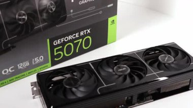 Poznan, Polonya - 27 Mart 2025: Çağdaş ASUS GeForce RTX 5070 grafik kartı arka planda perakende paketleme kutusu ile beyaz bir yüzey üzerinde gösteriliyor