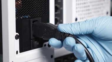 Mavi eldivenli birinin beyaz bir masaüstü bilgisayar çantasının PSU prizine güç kablosu taktığı yakın çekim görüntüsü. Dikkatli donanım kullanımını vurgular