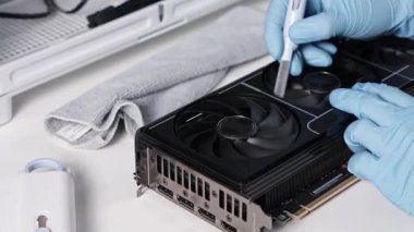 Poznan, Polonya - 30 Mart 2025: Mavi eldivenli bir teknisyen bakım sırasında soğutma vantilatörünü nazikçe temizlemek için pamuk çubuğu kullanıyor. Kurulum beyaz bir masaya yerleştirilir.