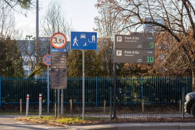 Poznan, Polonya - 15 Mart 2025: Yaya alanı sembolü, ağırlık sınırı, fiyat listesi ve Park & Go erişilebilirlik tabelaları sonbahar kent ortamında karayolu ve ağaçlarla gösteriliyor