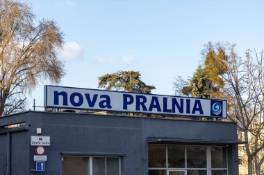 Poznan, Polonya - 15 Mart 2025: Arkaplanda ağaçlarla gündüz yakalanan koyu mavi harflerle ve girdap ikonuyla gri binanın dış yüzeyindeki Yeni Çamaşır Servisi imzası