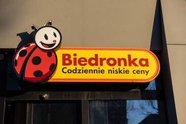 Poznan, Polonya - 15 Mart 2025: Biedronka mağaza tabelası gülen uğur böceği logosu ve günlük düşük fiyatlı slogan modern süpermarket girişinin dışındaki parlak sarı arka planda