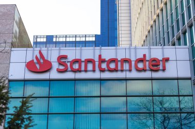 Poznan, Polonya - 15 Mart 2025: Posnan iş bölgesinde cam cepheli ve kırmızı logolu modern ofis binasının kumlu banka tabelası