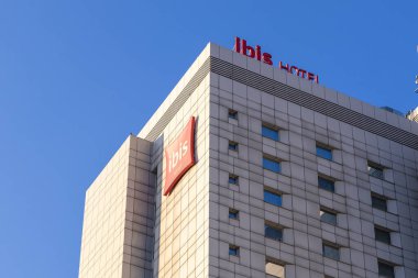 Poznan, Polonya - 15 Mart 2025: Gündüz güneşli kentsel mimari perspektifinde kırmızı logo ve dikdörtgen pencereli modern Ibis otel binası cephesi